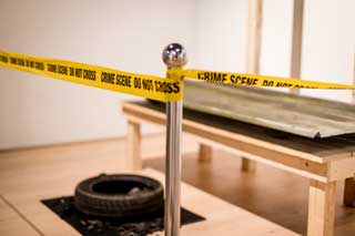 Eine Stelle die mit gelbem Abspeerband mit der Schrift "Crime Scene - Do not Cross" abgesperrt ist.