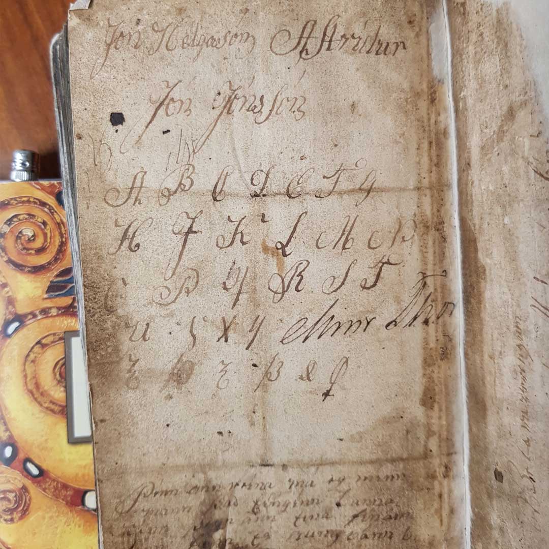 Ein Foto einer isländischen Psalmensammlung von 1754. Abgebildet ist eine Seite mit einem handschriftlich eingetragendem Alphabet samt Sonderzeichen.