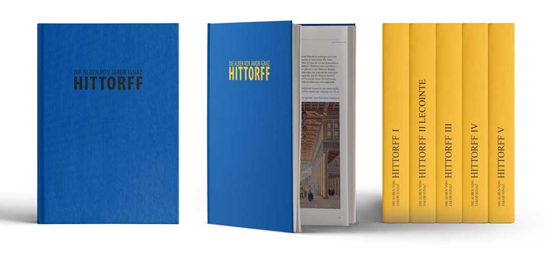 Foto von mehreren Bänden aus der Sammlung Jakob Ignaz Hittorff. Die Bücher sind zum einen dunkelblau und die Buchrücken sind gelb.