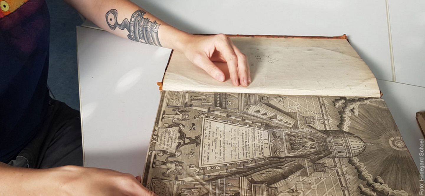 Ein Foto eines historischen Buches und Händen, die das Buch öffnen.