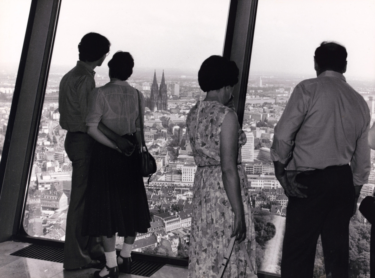 Foto von 4 Personen die sich auf der Aussichtsplattform des Fernsehturms "Colonius" befinden, mit der Sicht auf Köln-Neustadt-Nord.