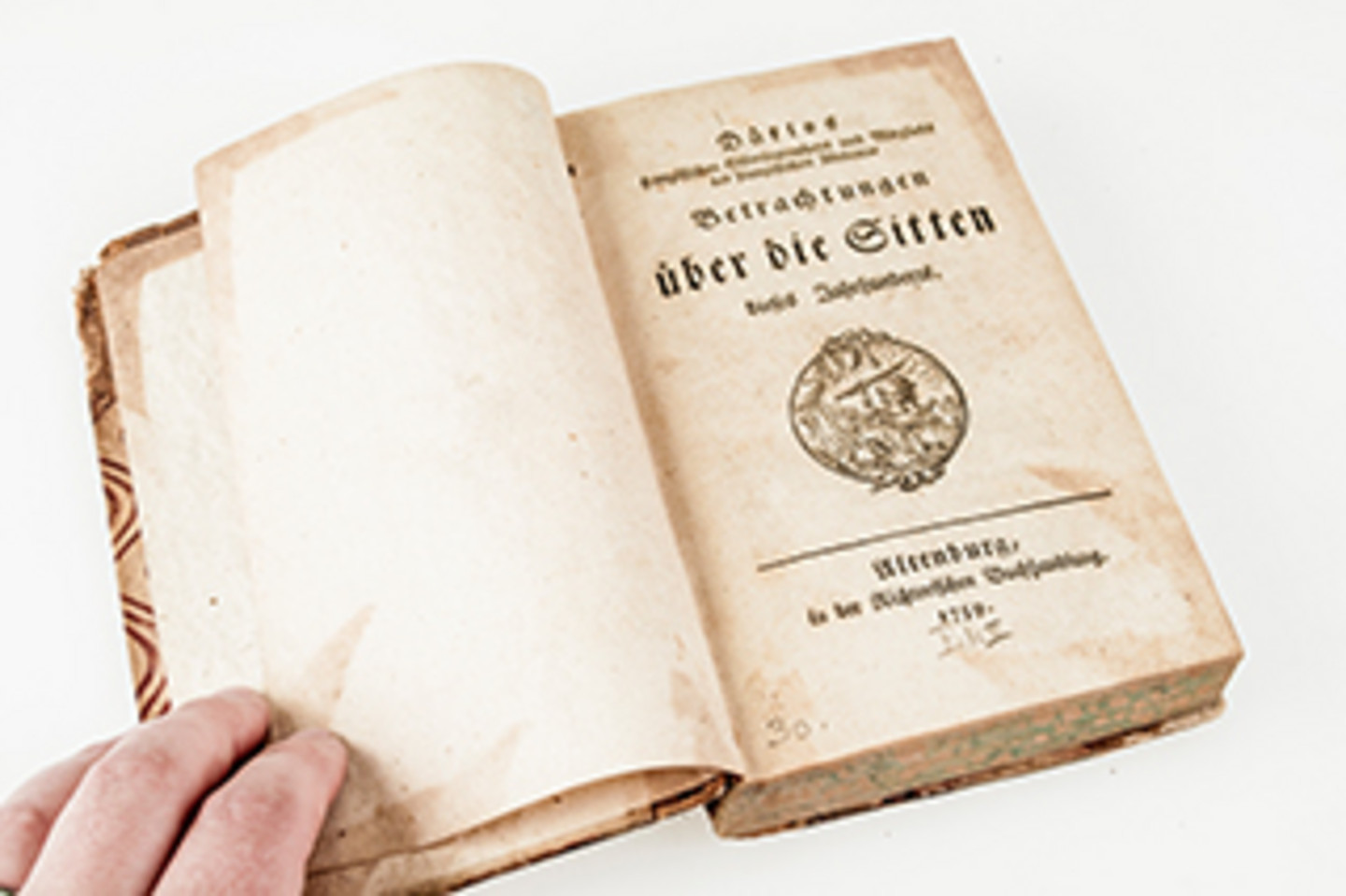 Foto eines offenen Buches mit dem Titelblatt "Betrachtungen über die Sitten dieses Jahrhunderts". Darunter befindet sich eine Art Wappen.