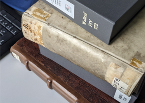 Photo of historical books stacked on top of each other.