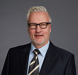 Portraitbild von Thomas Bähr, graue Haare, Brille, Anzug