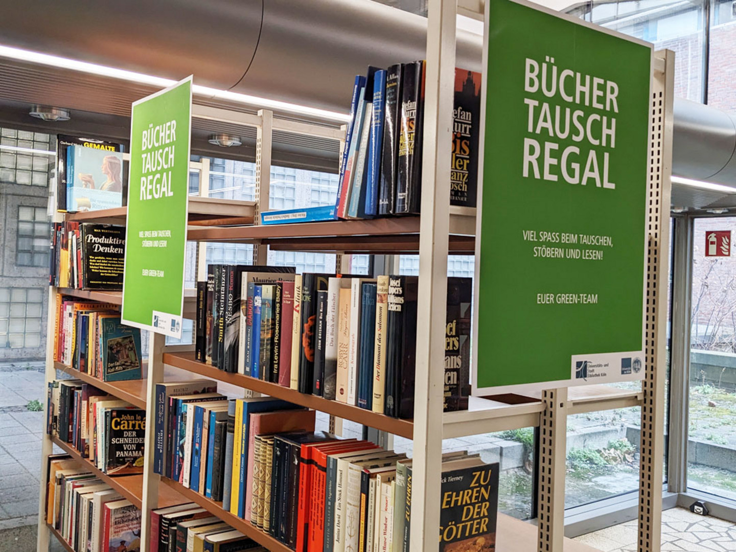Ein Foto des befüllten Büchertauschregales im Foyer der USB Köln.