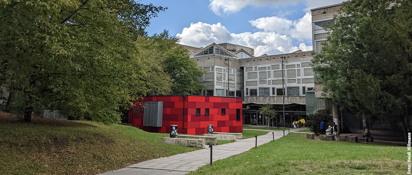 Aussenansicht des Bibliotheksgebäudes mit rotem Kubus im Vordergrund