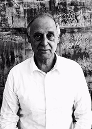 Schwarz-weißes Porträt von Walter Thöning. Er steht vor einer steinartigen Wand und trägt ein helles Hemd.